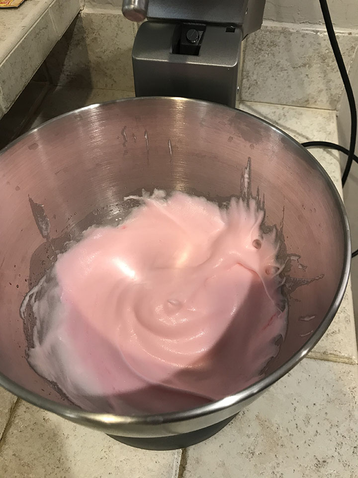 Meringue with pink food coloring in mixing bowl