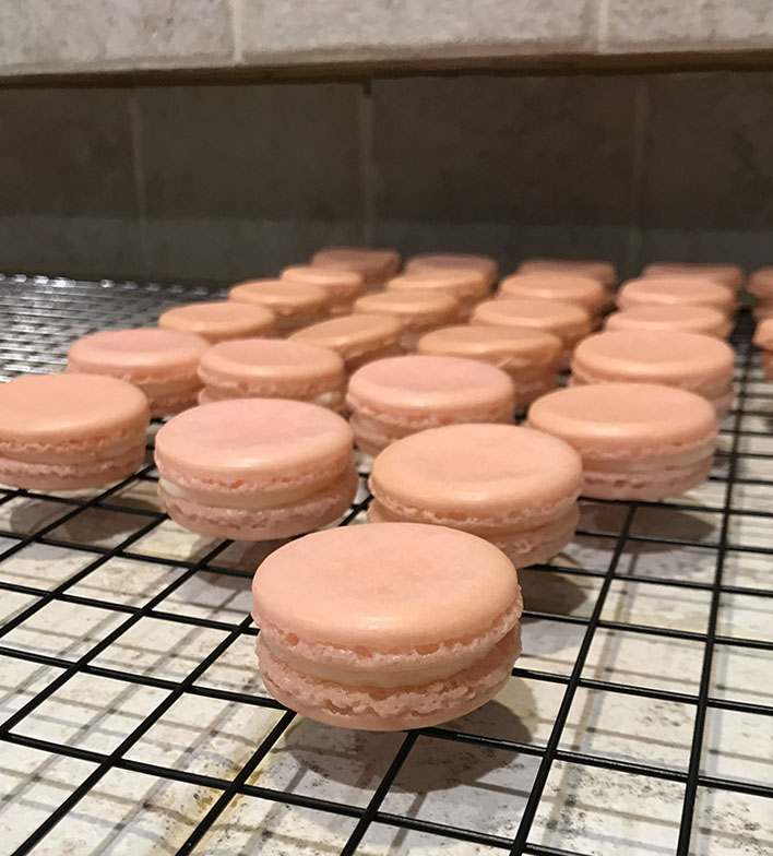 Pink macarons with buttercream on rack